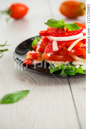 salad of fresh red tomatoes with onions 117170983