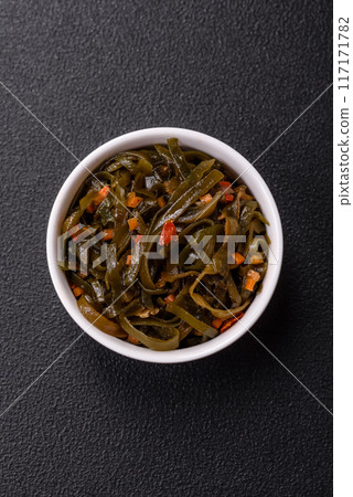 Delicious marinated seaweed with paprika, spices and salt on a dark concrete background Delicious marinated seaweed with paprika, spices and salt on a dark concrete background 117171782
