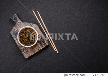 Delicious marinated seaweed with paprika, spices and salt on a dark concrete background 117171788