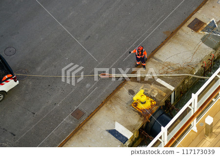 The process of mooring a large ship at the harbor pier, pulling the rope ashore using a pickup The process of mooring a large ship at the harbor pier, pulling the rope ashore using a pickup 117173039