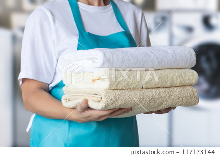 Cleaning lady in blue apron with towels . 117173144