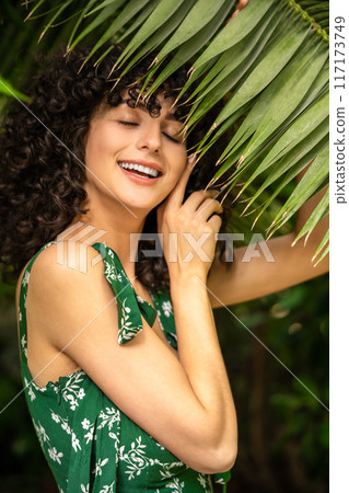 Woman on a background of tropical leaves creates expressing summer freshness Woman on a background of tropical leaves creates expressing summer freshness 117173749