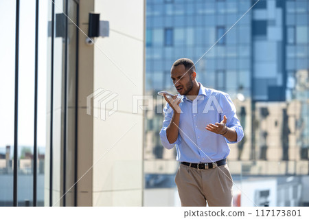 Man wearing formal wear talking on smartphone while walking in city street 117173801