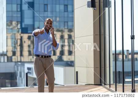 Confident man wearing blue shirt talking on mobile phone having business conversation Confident man wearing blue shirt talking on mobile phone having business conversation 117173802