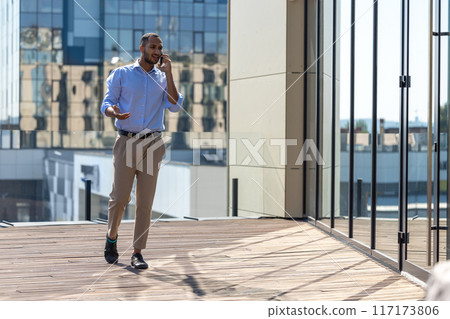 African American businessman using mobile phone in city street 117173806