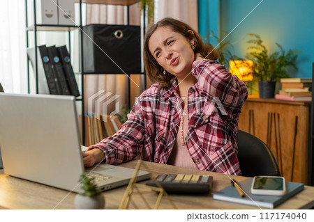Tired businesswoman suffers from spine neck muscle pain at home office workplace overworking 117174040