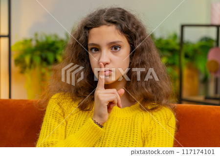 Teenager child girl presses finger to lips makes silence hush sign do not tell gossip secret, quiet 117174101