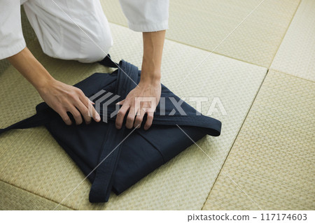 A man in a judo uniform folding his hakama A man in a judo uniform folding his hakama 117174603