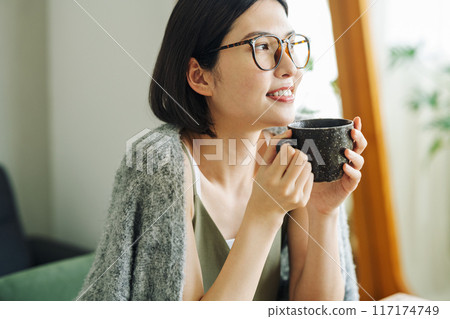 Woman drinking hot coffee at home 117174749