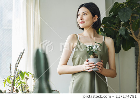 Woman holding a potted plant in a room Woman holding a potted plant in a room 117174781