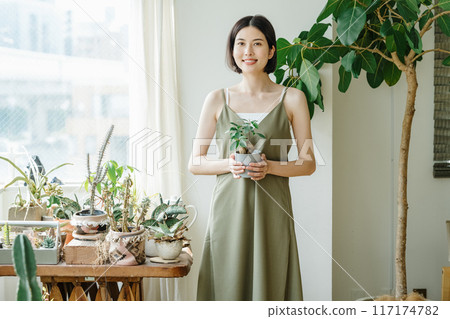 Woman holding a potted plant in a room Woman holding a potted plant in a room 117174782