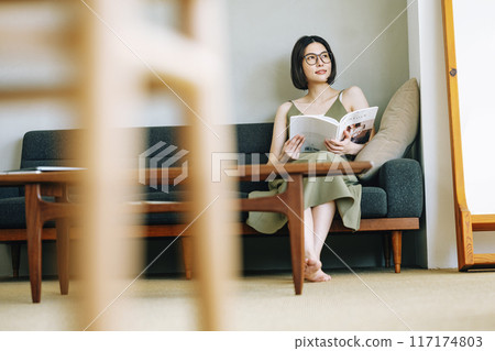 A woman reading a magazine on the sofa 117174803