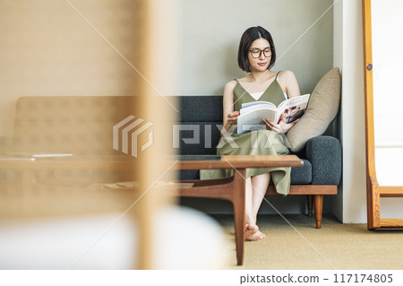 A woman reading a magazine on the sofa A woman reading a magazine on the sofa 117174805