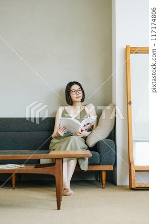 A woman reading a magazine on the sofa 117174806