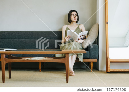 A woman reading a magazine on the sofa A woman reading a magazine on the sofa 117174808