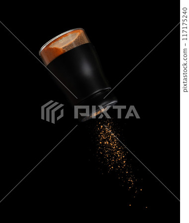 Chilli seasoning powder flavor falling from shaker bottle, red chilli and seasoning powder splash in mid air. Seasoning powder shaker spice up taste of food over black background isolated 117175240