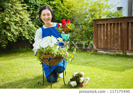 A smiling middle-aged woman planting flowers A smiling middle-aged woman planting flowers 117175490