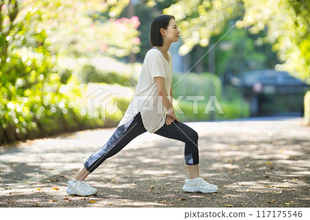 穿著運動服的微笑的年輕女子伸展身體 穿著運動服的微笑的年輕女子伸展身體 117175546