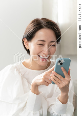 看著智能手機在客廳裡的中年女人 117176383
