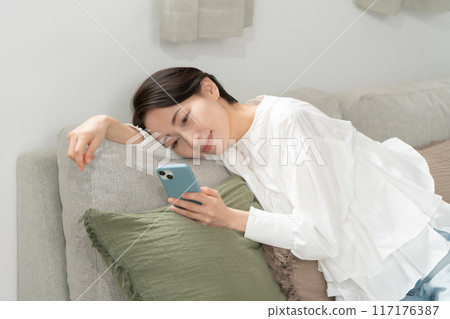 看著智能手機在客廳裡的中年女人 117176387