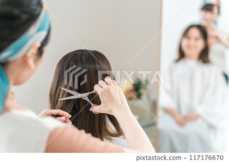 A woman who came to a beauty salon and a hairdresser/barber who cuts hair 117176670