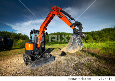 bulldozer stands on a piece of land against the backdrop of a bright blue sky and green trees. construction equipment ready to work bulldozer stands on a piece of land against the backdrop of a bright blue sky and green trees. construction equipment ready to work 117176817