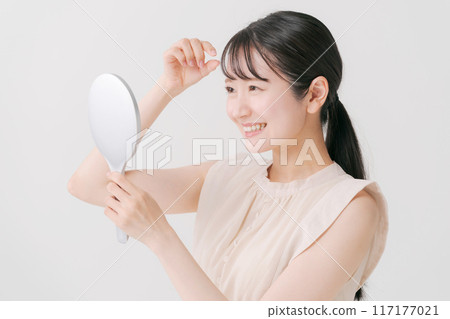 A woman in her twenties looking in the mirror 117177021