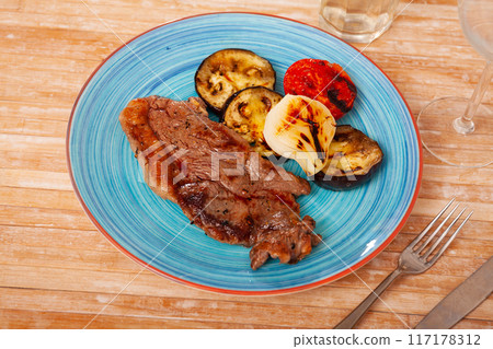 Grilled beef steak with grilled eggplant, onion and tomatoes 117178312