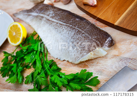 Fresh cod fillet with parsley on wooden board 117178315