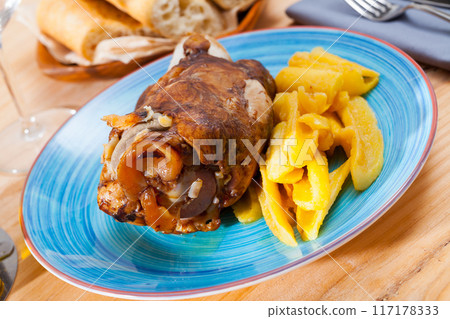 Baked pork knuckle with potatoes served on blue plate Baked pork knuckle with potatoes served on blue plate 117178333