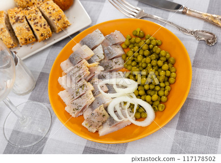 Pieces of herring with peas served on plate 117178502