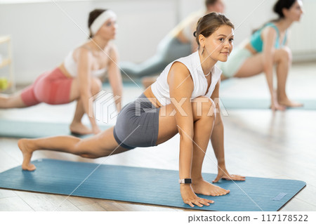 Group of women doing body stretching during Pilates class in studio 117178522