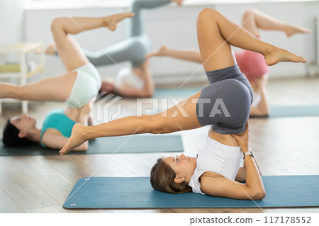 Girls practicing yoga performing Ardha Navasana, or half boat pose, balancing asana to strengthen abdominal muscles 117178552