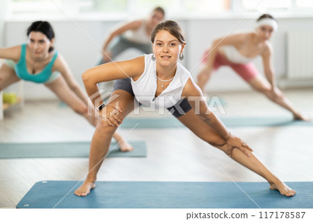 Young woman during Pilates strength training standing performs exercises 117178587