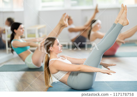 Young girl practicing boat position in pilates studio Young girl practicing boat position in pilates studio 117178758