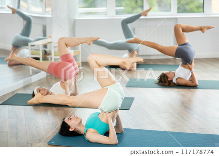 Together with coach, girls perform inverted asanas, move from lying position to plow asana Together with coach, girls perform inverted asanas, move from lying position to plow asana 117178774