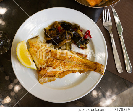 Fried common sole with lemon and baked vegetables 117178839