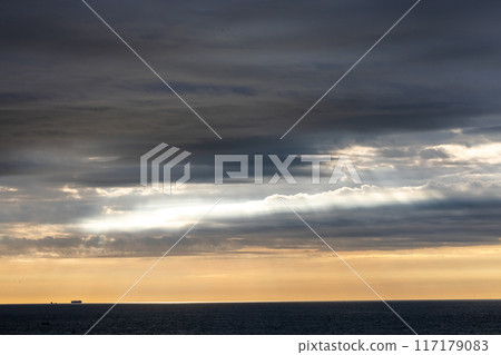The sunrise creates a scenic view with dramatic cloud cover over the ocean horizon 117179083
