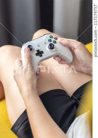 The woman is holding a white jostic, joystick, navigation key, cursor buttons, navigation control. She plays the game on the console. Close up vertical 117179757