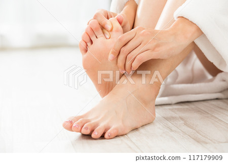A woman massaging the soles of her feet. A woman massaging the soles of her feet. 117179909