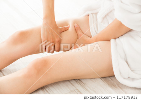 A woman is massaging her thighs. 117179912
