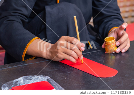 Human using calligraphy brush painting on lucky money red envelope 117180329