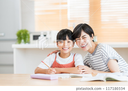 A girl and her mother studying in the living room. 117180334
