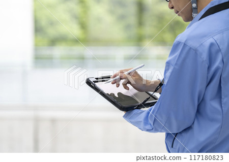 Hand of a man in work clothes typing on a tablet with a pen Hand of a man in work clothes typing on a tablet with a pen 117180823