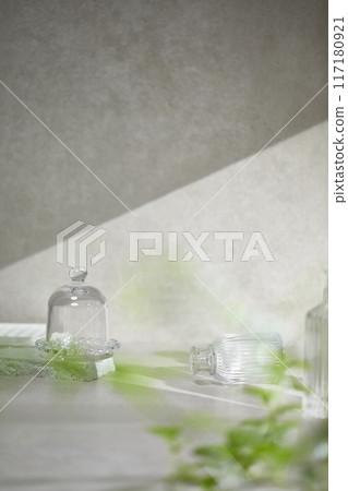 A gray-toned tile background with various props with sunlight coming through the window. 117180921