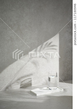 A gray-toned tile background with various props with sunlight coming through the window. 117180946