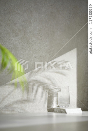 A gray-toned tile background with various props with sunlight coming through the window. 117180959