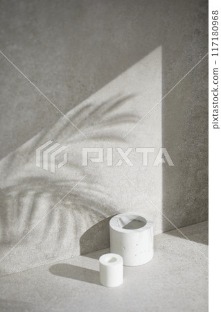 A gray-toned tile background with various props with sunlight coming through the window. 117180968