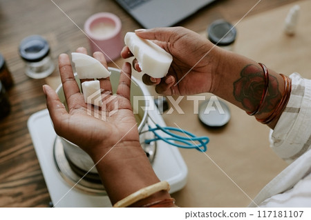 Close-up of hands crafting homemade soap with natural ingredients from above. This image captures intricate process of soap making with various tools present on wooden surface Close-up of hands crafting homemade soap with natural ingredients from above. This image captures intricate process of soap making with various tools present on wooden surface 117181107