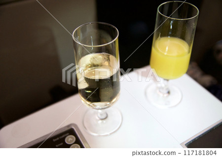 ZURICH, SWITZERLAND - JUNE 22, 2019: Welcome drink with sparkling wine and orange juice in business class during a long-haul flight in an airplane ZURICH, SWITZERLAND - JUNE 22, 2019: Welcome drink with sparkling wine and orange juice in business class during a long-haul flight in an airplane 117181804